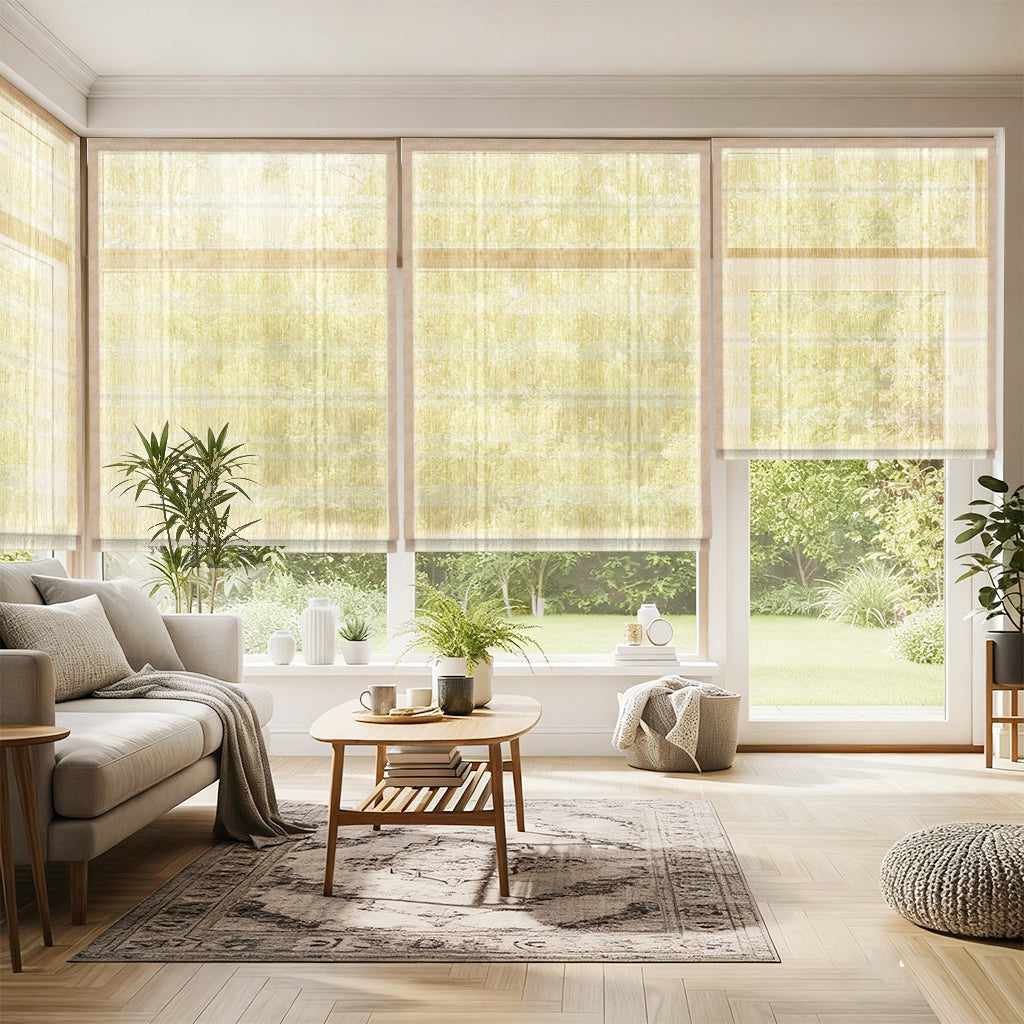 Motorized woven wood shades in bright living room with beige sofa, wooden coffee table, pouf, potted plants, and large windows overlooking green backyard.