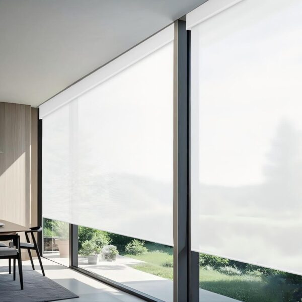 Motorized light-filtering roller shades in modern living room with dining area, large windows, and view of green backyard garden.