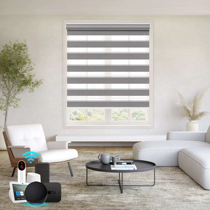 Motorized zebra roller shades in modern living room with white sectional sofa, round coffee table, and smart home voice control devices, overlooking green landscape.